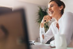 Smiling,Woman,Sitting,At,Her,Desk,In,Office.,Happy,Business